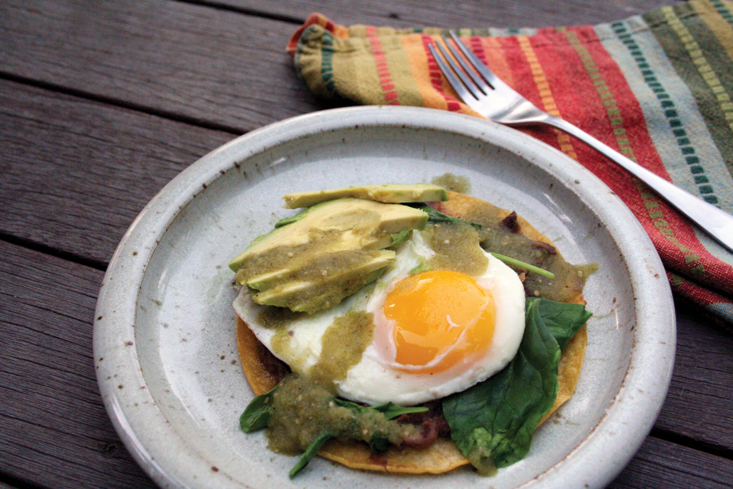 Plate of huevos rancheros with salsa and avocado.
